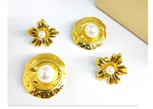 Detailed view of luxury gold-tone metal flower and round pearl earrings set, elegant design.