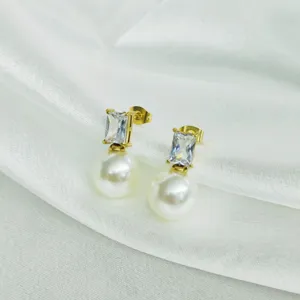 Close-up detail of elegant gold-plated stud earrings featuring cubic zirconia and white faux pearls.