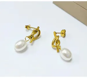 Detailed view of gold knotted earrings with white pearl pendants, elegant and chic jewelry style.