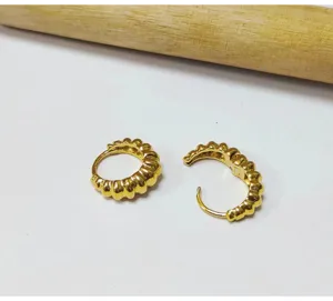 Vue detaillee de boucles d'oreilles creoles cotelees plaquees or avec texture elegante.