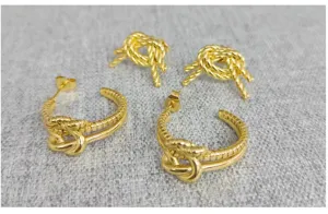 Close-up detail of stainless steel 18k gold plated knot twist earrings and studs set texture.