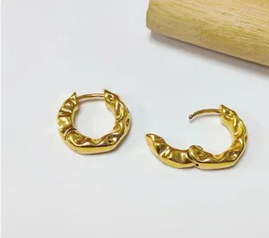 Gros plan sur les boucles d'oreilles créoles dorées texturées au design de coupe en bambou.