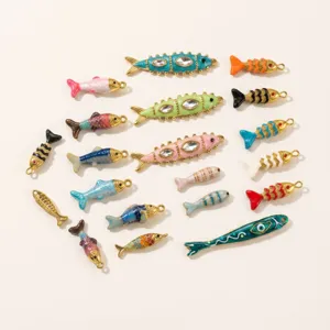 Nahaufnahme von bunten emaillierten Fisch Anhängern, vergoldet für DIY Schmuck Design.