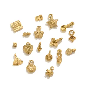 Vista detallada de varios dijes mini de acero inoxidable dorado y accesorios de joyeria.