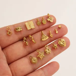 Vista detallada de mini dijes dorados, estrellas y corazones para joyeria de bricolaje.