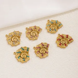Primer plano de dijes de concha de ammonites dorados con pedrería colorida para joyería.