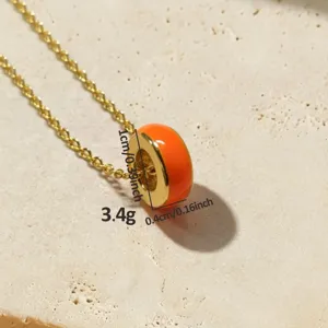 Detailopname van de levendige oranje ronde hanger ketting voorzien van een fijne goudkleurige ketting.