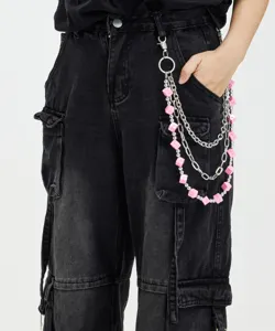 Detail shot of multi-layer metal pants chain with pink cube charms for hip-hop streetwear style.