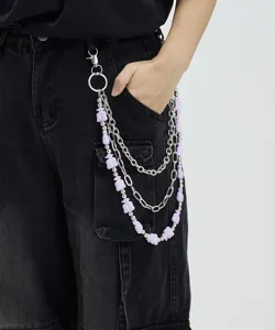Close-up detail of a 3-layer hip-hop pants chain with purple money bag charms on dark denim.