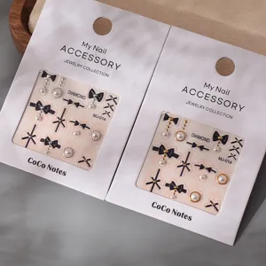 Exquisite black bow nail art charms with pearls and metal accents for luxury manicure design.