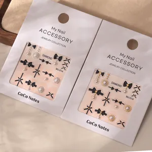 Black bow nail art stickers with pearls and metallic gold charms for elegant manicure designs.