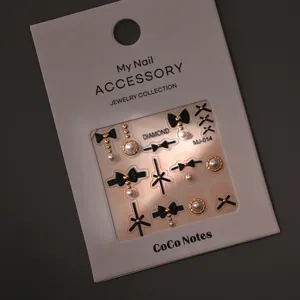 Detailed view of luxury black bow nail art stickers with pearls and metallic gold diamonds.