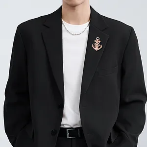Close-up detail shot of a stylish rose gold anchor helm brooch pinned on a black suit jacket.