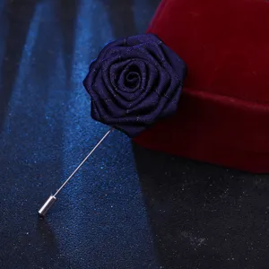 Détail de broche rose en tissu bleu foncé, boutonnière élégante pour costume de mariage formel.