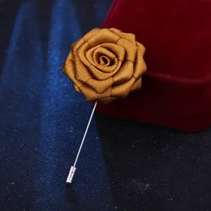 Gros plan d'une broche rose en tissu bronze, avec des pétales de soie délicats et une tige en métal.