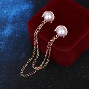 Detail shot of delicate white pearl collar pins featuring elegant metal tassel chains.