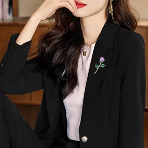 Close-up detail shot of the elegant purple rose brooch worn on a black blazer lapel.