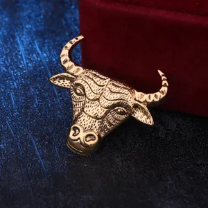 Primer plano de un broche vintage de cabeza de toro dorada con intrincada textura metálica.