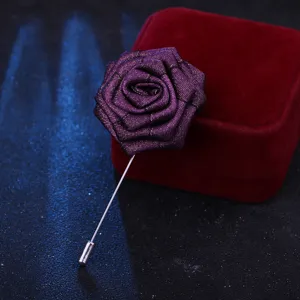 Gros plan d'une élégante broche rose en tissu mauve avec épingle argentée sur boîte en velours.