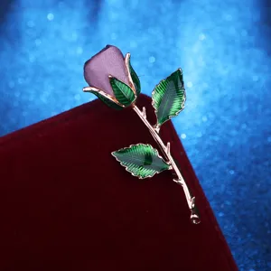 Exquisite rose brooch detail close-up, fabric flower with enamel leaves and thorny stem.