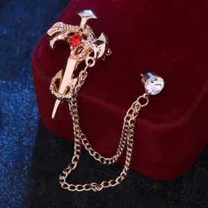 Close-up detail van vintage gouden slang zwaard broche met rode kristallen en hangende ketting.