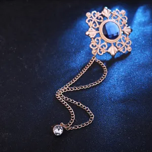 Nahaufnahme der goldenen Vintage-Brosche mit dunkelblauem Stein filigranem Muster und Kette.