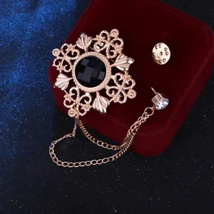 Nahaufnahme einer goldenen Vintage Brosche mit schwarzem Stein und Kette für Mäntel.