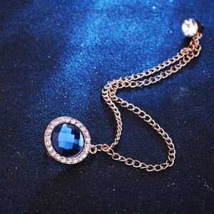 Nahaufnahme einer stilvollen blauen Strass-Rundbroche mit Metallkette für elegante Herrenanzüge.