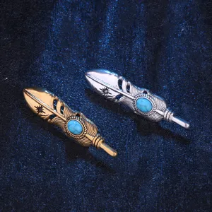 Close up detail of vintage retro feather brooch, metallic texture with blue turquoise stone inlay.