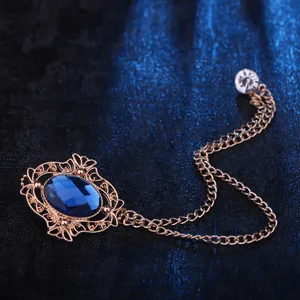 Vintage blue gemstone brooch detail close-up, showing elegant filigree metal frame and chain.