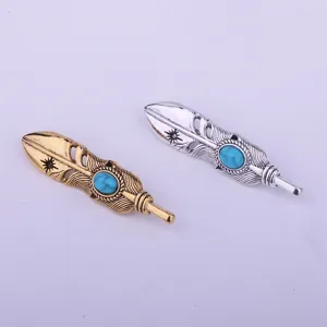 Close-up detail of retro feather brooches with turquoise stones in gold and silver finishes.