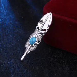 Detailed close-up of vintage silver feather brooch with turquoise stone, retro jewelry accent.