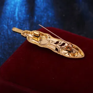 Vintage gold feather brooch back detail close-up, elegant hollowed-out metal design.