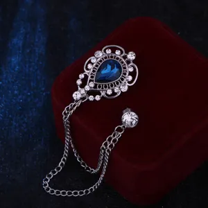 Durchbrochene Tropfenbrosche mit blauem Strass und Metallkette, elegantes Modeaccessoire.