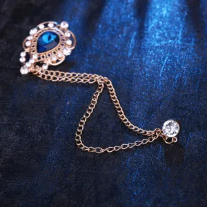 Antike goldfarbene Metallbroche mit blauem Tropfen-Strassstein und doppelten Ketten für Kleidung.