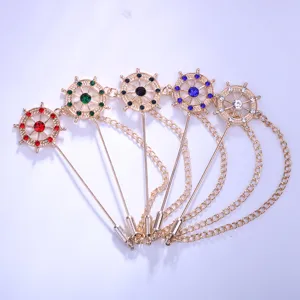 Detail view of metallic rudder lapel pin with colorful rhinestones and hanging chain, suit accessory.