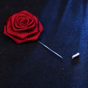 Gros plan detail de la broche fleur rose en tissu rouge avec epingle metal pour mariage.