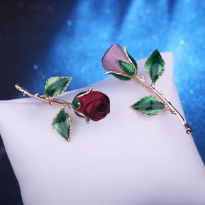 Close-up detail of fabric rose brooch with green leaves and gold stem for evening dress party.