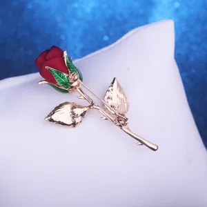 Close-up detail shot of a elegant rose brooch featuring fabric flower and golden stem.