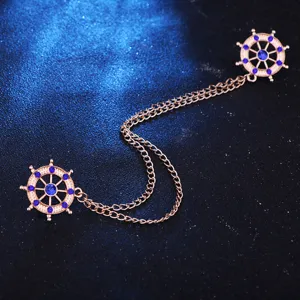 Close-up detail of double steering wheel collar chain brooch with blue rhinestones and tassels.