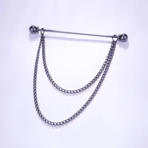 Detailopname van de metalen kraagspeld met donkere afwerking en dubbele hangende kettingen.