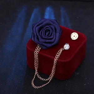 Nahaufnahme der eleganten blauen Stoff-Rosenbrosche mit einer zarten hängenden Kette.