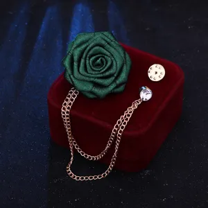 Nahaufnahme einer eleganten gruenen Stoffrosen Brosche mit Quasten Kette auf Samtbox.