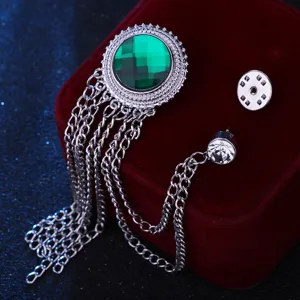 Close-up of retro silver tassel brooch with green faceted gem, exquisite suit accessory detail.