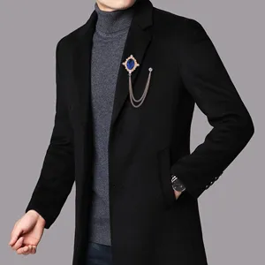 Nahaufnahme einer Herren Vintage Kreuz Brosche mit Kette und Quaste am Mantelrevers.