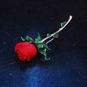 Nahaufnahme der eleganten roten Rosenbrosche mit funkelnden grünen Kristallstielblättern.