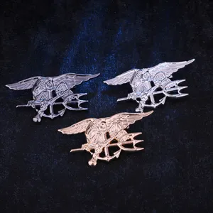 Gros plan detaille de badges epingles en metal pour hommes avec un design aigle et trident.