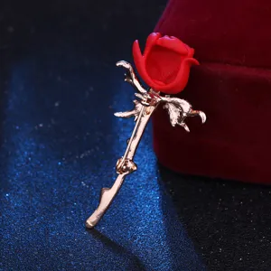 Exquisites Rosenbroschendetail mit zartem rotem Blütenkopf und poliertem Goldstiel.