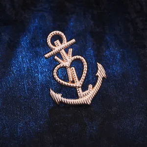 Détail en gros plan d'une élégante broche ancre et cœur en or rose, accessoire de mode chic.