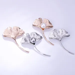 Vista detallada de exquisitos broches de hoja de ginkgo con perlas elegantes y acabados metálicos.